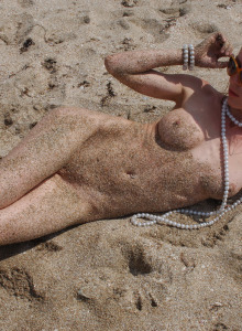 Nude blonde playing with the sand on the beach